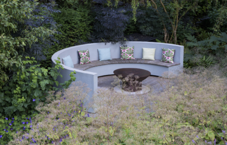 View across mature garden to curved seating and fire pit