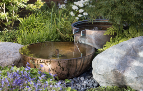 Copper Water feature with lush planting and boulders