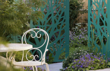 green metal screens in tree design lead to garden