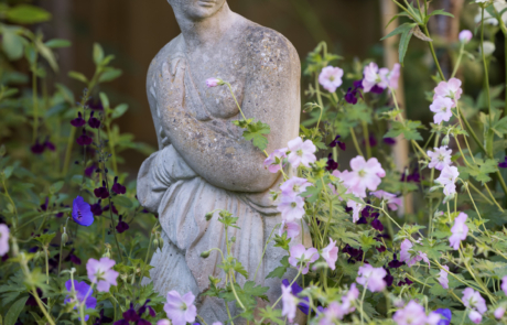Statue of lady in garden amongst pretty flowers