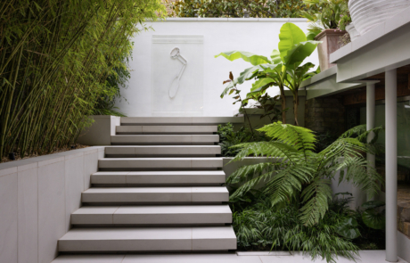 City Courtyard garden with Porcelain floating steps leading to wall art on rendered wall. Tropical planting either side of steps.