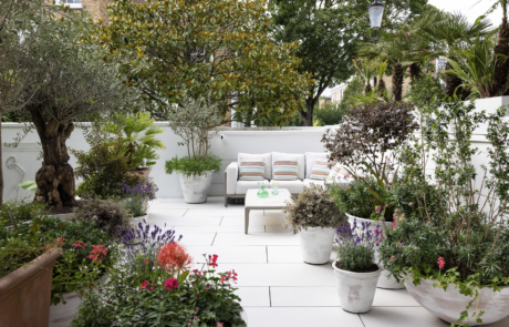 London Roof garden with outdoor sofa, coffee table, whitewashed pots and colourful Mediterranean plants.